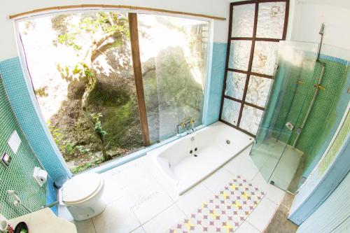 a bathroom with a tub and a large window at Suítes Casa Grande in Abraão