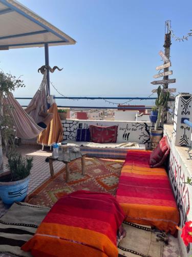 un patio con sofá y una mesa con almohadas en Agachill Surf House, en Tamraght Ouzdar