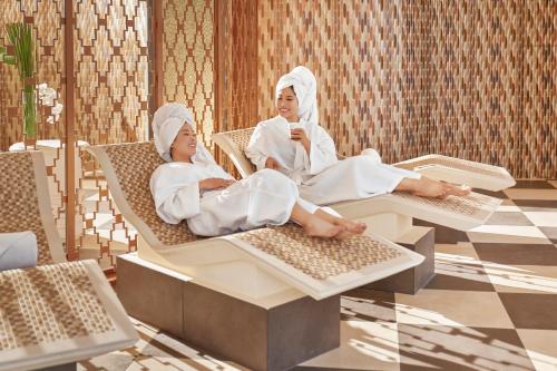 two women are sitting in chairs in a room at InterContinental Grand Ho Tram in Ho Tram