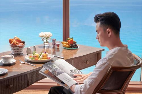 a man sitting at a table reading a book at InterContinental Grand Ho Tram in Ho Tram