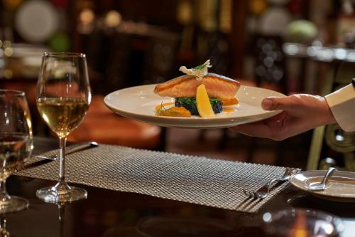 a person holding a plate of food and a glass of wine at InterContinental Grand Ho Tram in Ho Tram