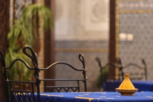 a table with a blue table cloth and a yellow vase on it at Riad Youssef in Fès