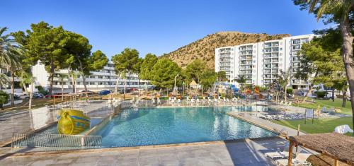 a large swimming pool with chairs and a building at BelleVue Club in Port d'Alcudia