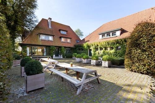 a patio with picnic tables in front of a house at Guesthouse Brouwershuis in Poperinge