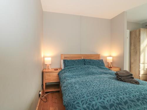 a bedroom with a bed with a blue comforter and two lamps at 24 Heron Court in Bridport