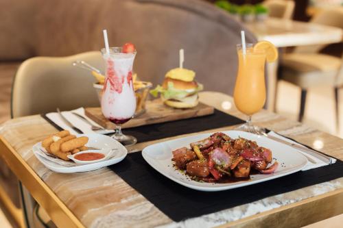 a table with two plates of food and two drinks at Hotel MeraPrime Gold Lisboa in Lisbon