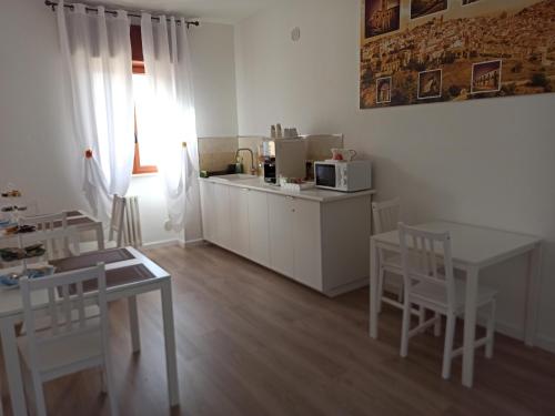 una cucina con armadi bianchi, tavolo e sedie di A Due Passi a Grassano