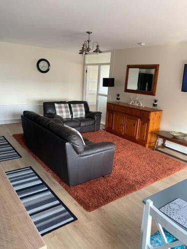 a living room with a leather couch and a television at Kennys apartment in Milford Haven