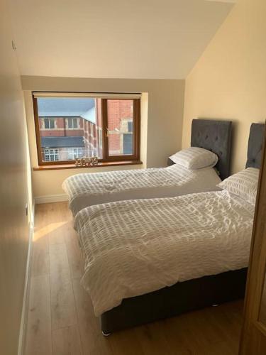 2 camas en un dormitorio con ventana en Kennys apartment, en Milford Haven