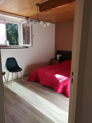 una camera con letto rosso e sedia di moulin de ROUCHILLOU a Saint-Martial-de-Valette