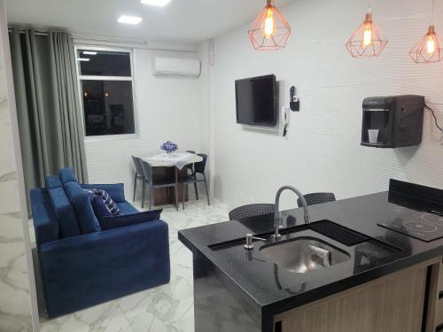 a kitchen with a sink and a living room with a table at Angra Inn, Angra dos Reis - Mar, Sol e Piscina in Angra dos Reis