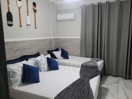 a room with two beds with blue pillows and utensils at Angra Inn, Angra dos Reis - Mar, Sol e Piscina in Angra dos Reis