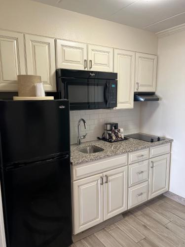 a kitchen with a black refrigerator and white cabinets at Dunes Suites Oceanfront in Ocean City