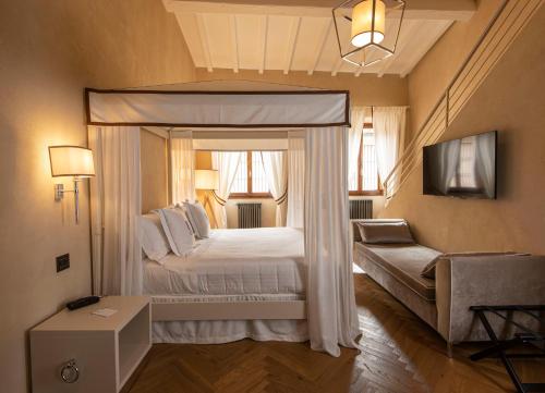 a bedroom with a canopy bed and a couch at Relais Uffizi in Florence