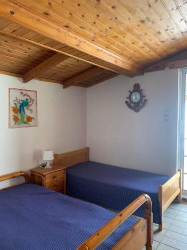 een slaapkamer met 2 bedden en een klok aan de muur bij Ξυλινο σπίτι δίπλα στην θάλασσα in Kineta