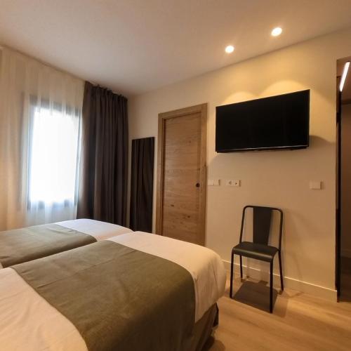 a hotel room with two beds and a television on the wall at Hotel Marfany in Andorra la Vella