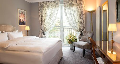 a bedroom with a bed and a desk and a window at Victor's Residenz-Hotel Saarbrücken in Saarbrücken