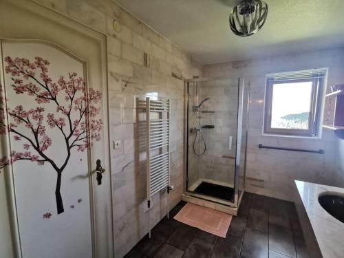 a bathroom with a shower with a tree mural on the wall at L'Estive, gîte à la ferme en montagne in Eschbach-au-Val