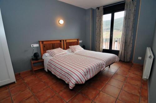 a bedroom with a bed with a striped blanket and a window at La Morada de San Millán in San Millán de la Cogolla