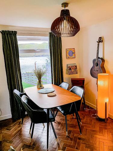 a dining room with a table and chairs and a guitar at This must be the place - Skye, Carbost in Carbost