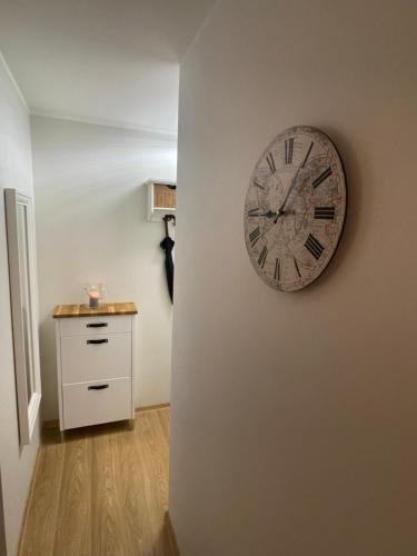 a clock hanging on a wall next to a dresser at Keskuse apartment with a balcony in Haapsalu