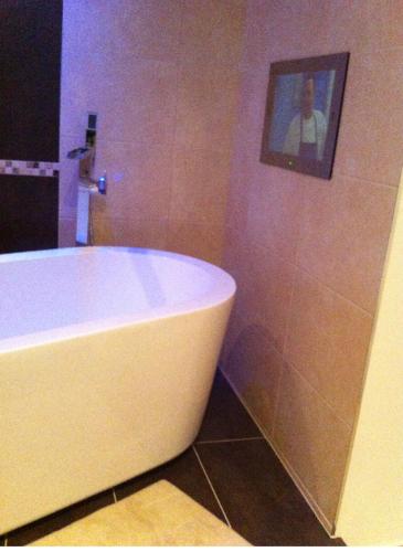 a bathroom with a white tub and a picture on the wall at Top floor in beautiful home in Radipole