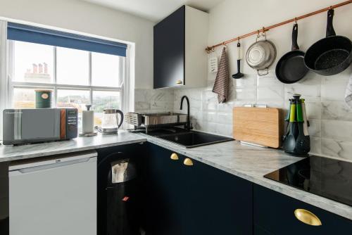eine Küche mit schwarzen Schränken und einer Arbeitsplatte in der Unterkunft Newly Renovated Central One-Bedroom, 99 Steps to the Sea in Brighton & Hove