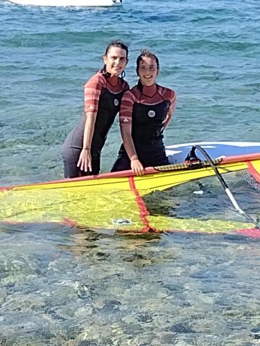 a man and woman sitting on a paddle board in the water at Afroessa Studios & Apartments in Samos