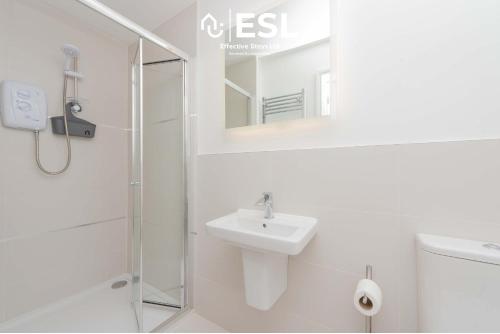 Un baño blanco con lavabo y ducha en Studio 1, First Floor Town Centre Apartment, en Shrewsbury