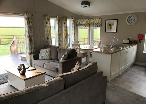a living room with a couch and a table and a kitchen at Larkrise Farm Lodges in Babcary