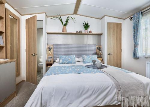 ein Schlafzimmer mit einem großen Bett mit blauen Kissen in der Unterkunft Willows Holiday Park in Withernsea
