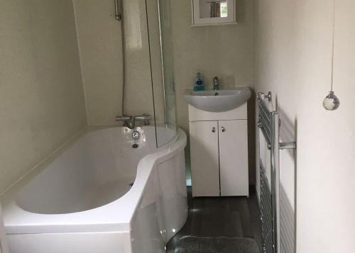 a bathroom with a white tub and a sink at Stream Valley Holiday Park in Penzance