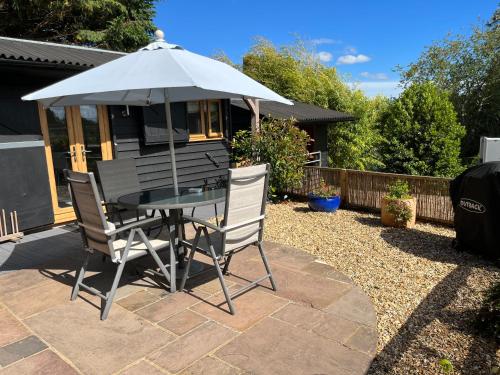 a table and chairs under an umbrella on a patio at Hascombe Accommodation in Hascombe