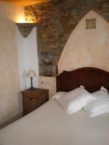 a bedroom with a bed and a stone wall at Hotel y Apartamentos Penarronda Playa in Castropol