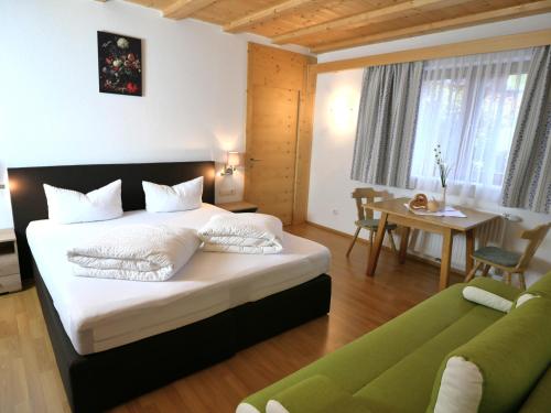 - une chambre avec un grand lit et un canapé vert dans l'établissement Stadlwirt Nauders, à Nauders