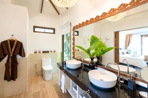 ein Badezimmer mit zwei Waschbecken und einem großen Spiegel in der Unterkunft Lanta Palace Beach Resort & Spa - Adult Only in Ko Lanta