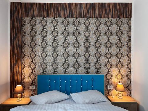 a bed with a blue headboard and a wall with at Casa Cojocaru in Cârcea