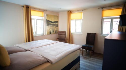 Schlafzimmer mit einem Bett, einem Stuhl und Fenstern in der Unterkunft Die FUHRMANN-SUITE, unser Deluxe-Apartment mit allem erdenklichen Komfort in Marktheidenfeld