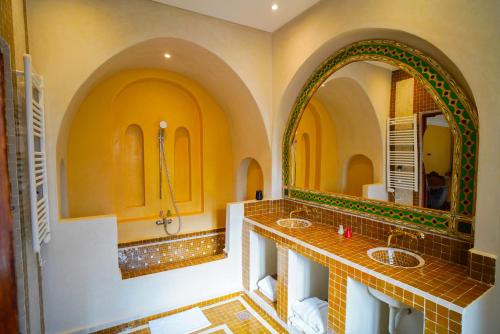 a bathroom with two sinks and two mirrors at Kasbah Hnini in Igdourane