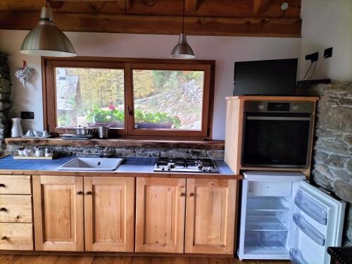 a kitchen with a stove and a window at Baita del noce in Mollia