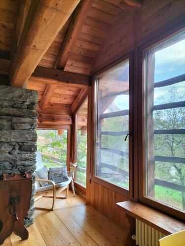 a living room with windows and a stone fireplace at Baita del noce in Mollia