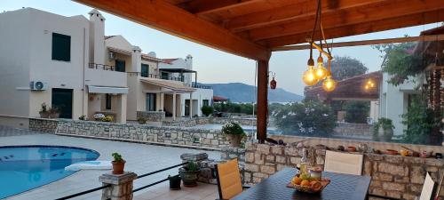 un patio con tavolo e sedie accanto alla piscina di Villa Viva a Asprouliánoi