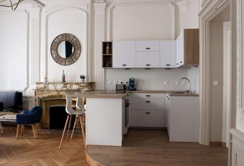 une cuisine avec des placards blancs, une table et une cheminée dans l'établissement Sublime appartement, chic et confortable., à Bourg-en-Bresse