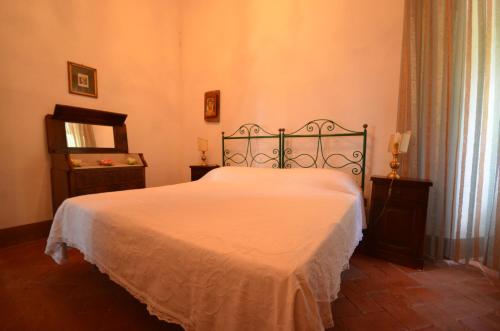 a bedroom with a white bed with a metal frame at Favolosa Villa in Toscana in Lucignano