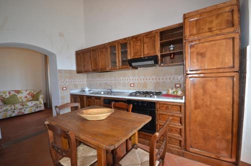 a kitchen with wooden cabinets and a wooden table at Favolosa Villa in Toscana in Lucignano