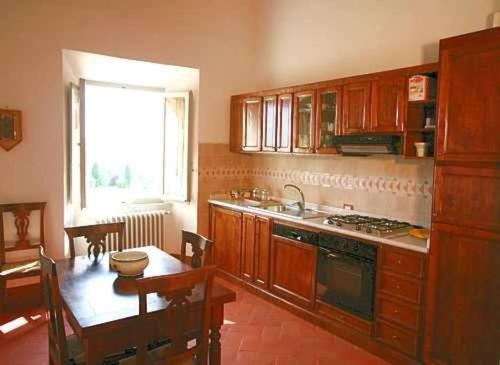 a kitchen with wooden cabinets and a table and a window at Favolosa Villa in Toscana in Lucignano