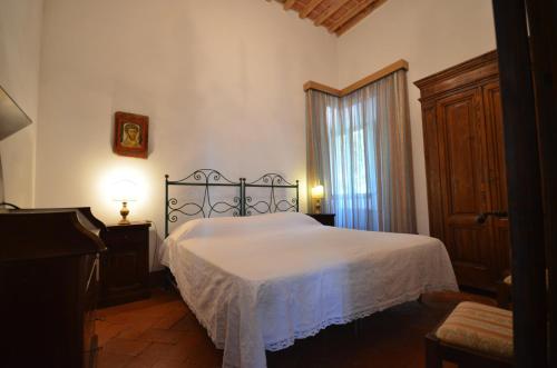 a bedroom with a white bed and a window at Favolosa Villa in Toscana in Lucignano