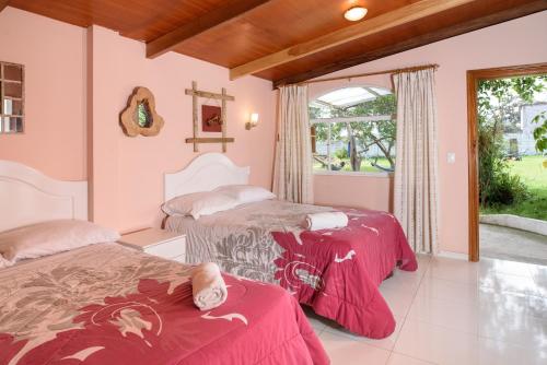 2 camas en una habitación con paredes rosas en Casa Elalu, en Quito