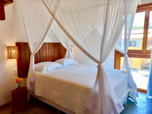 a bedroom with a white bed with a canopy at Oceà Privilegi - Taipu de Fora in Barra Grande