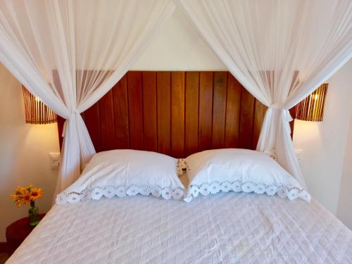 a bed with a canopy with white curtains at Oceà Privilegi - Taipu de Fora in Barra Grande